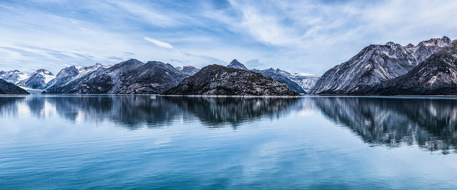 A panoramic view of glacier bay, mountains reflecting on the water