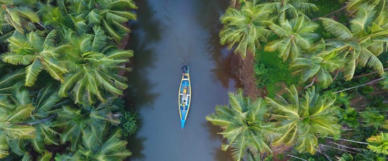Looking down at a lone boat travelling along on a river surrounded by rainforest