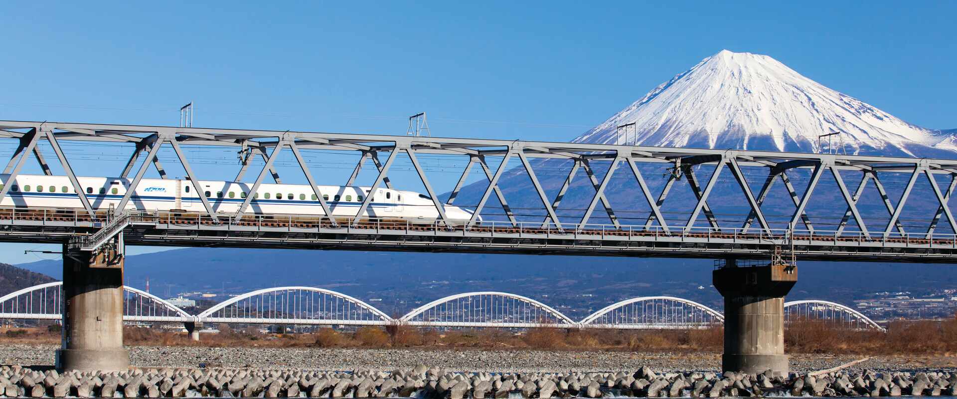 View of Bullet Train going over bridge in front of Mt Fuji, Japan