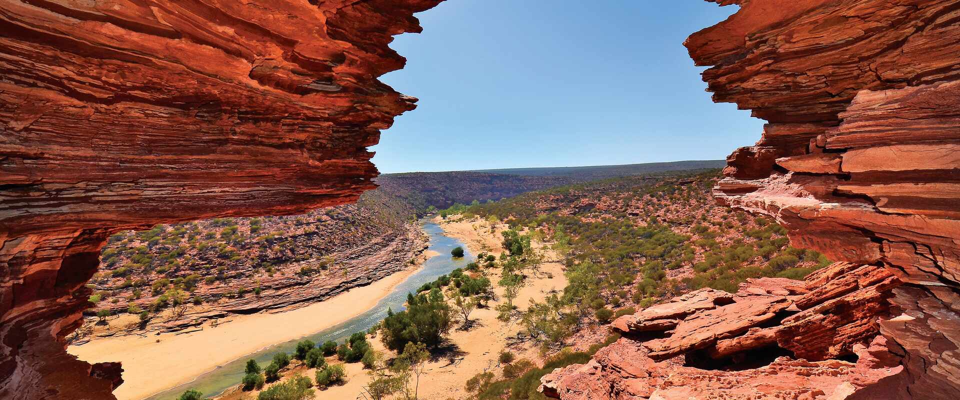 Distant view of river and surrounds seen between to red rock faces, Australia
