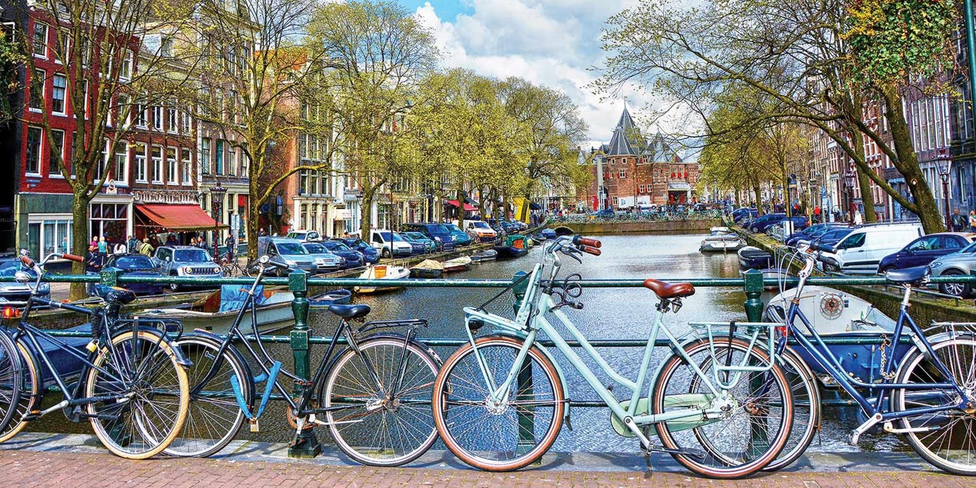 Colourful bikes resting against bridge railing, Amsterdam