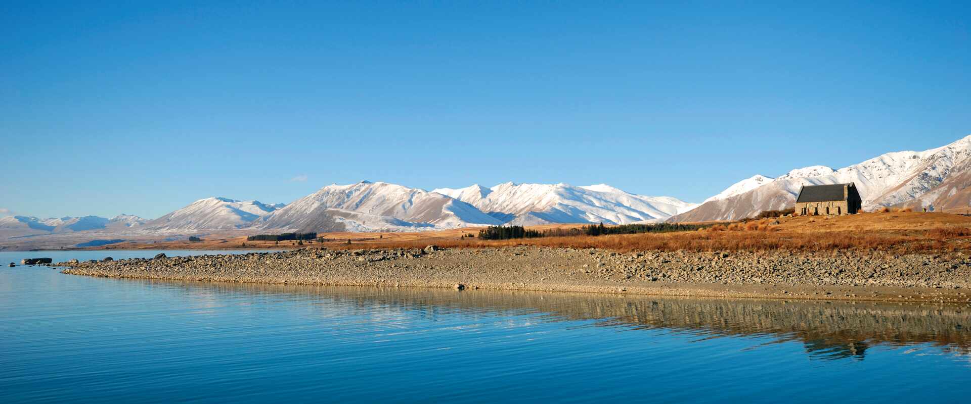 View of Lake Tekapo with the Church of the Good Shepherd and mountains in background, New Zealand