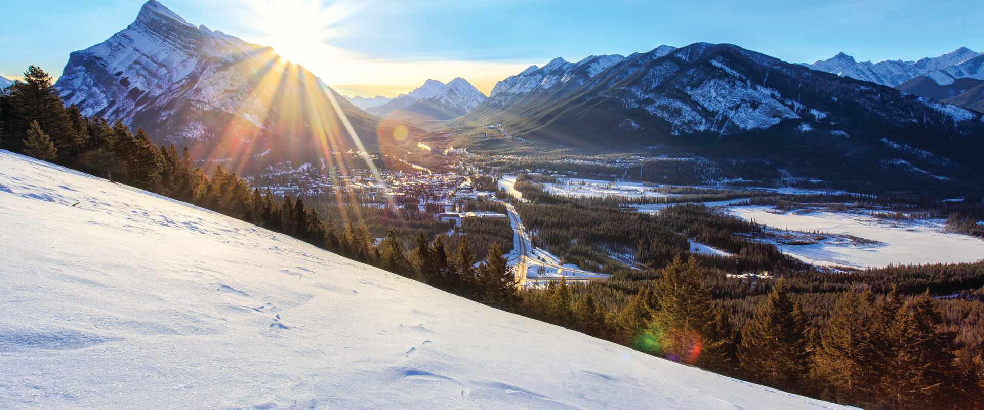 View of sunrise over snow covered ground and mountains, Canada