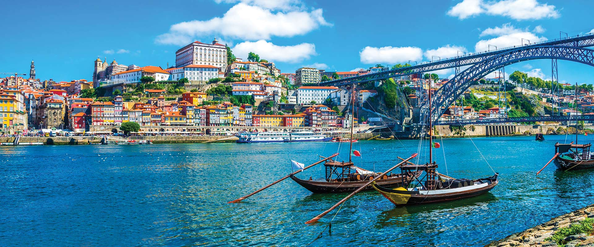 Two boats on river with city buildings in background, Porto