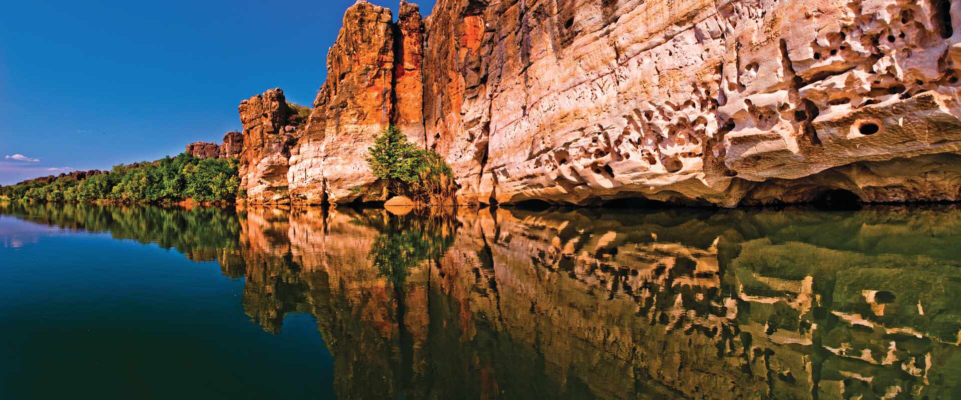 Red cliff face with reflection in the water, Australia